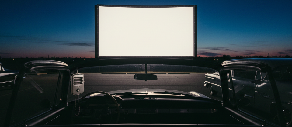 Front-row view from the driver's seat of a classic car at a drive-in theater at night, a giant glowing movie screen ahead and a drive-in speaker on the window